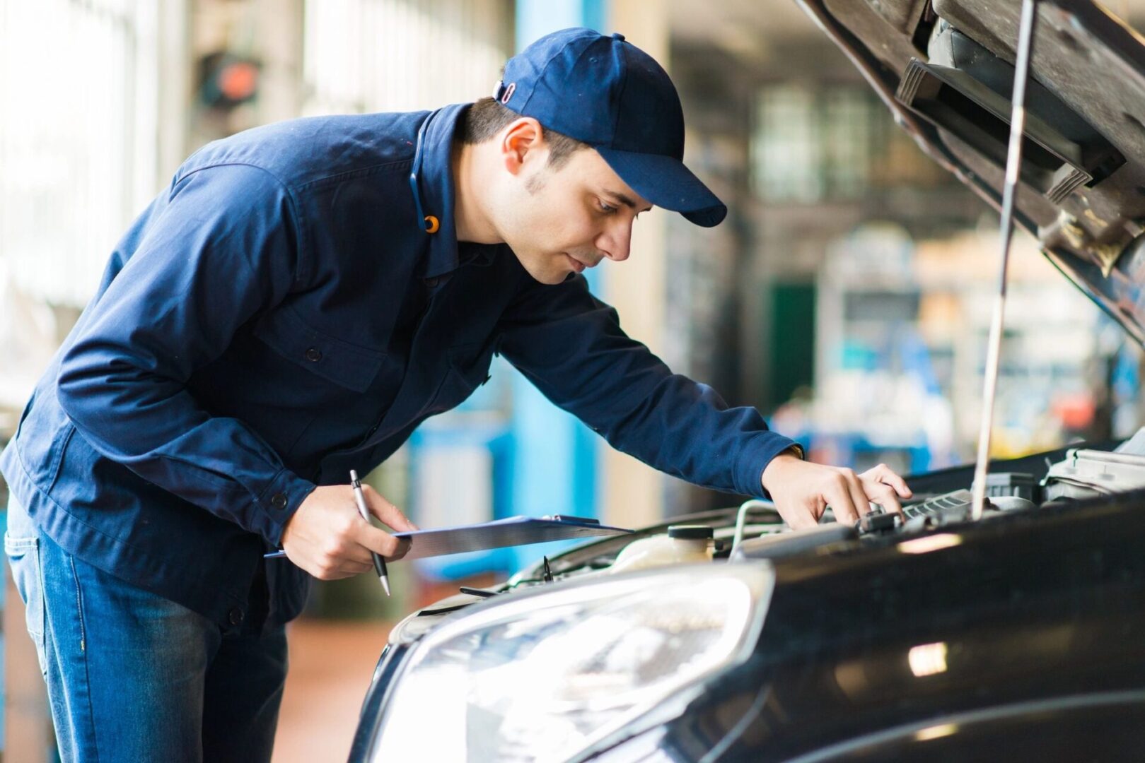 A man looking at a car engine bay and noting